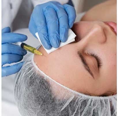 Gloved practitioner preparing to give a fine injection to the upper cheek
