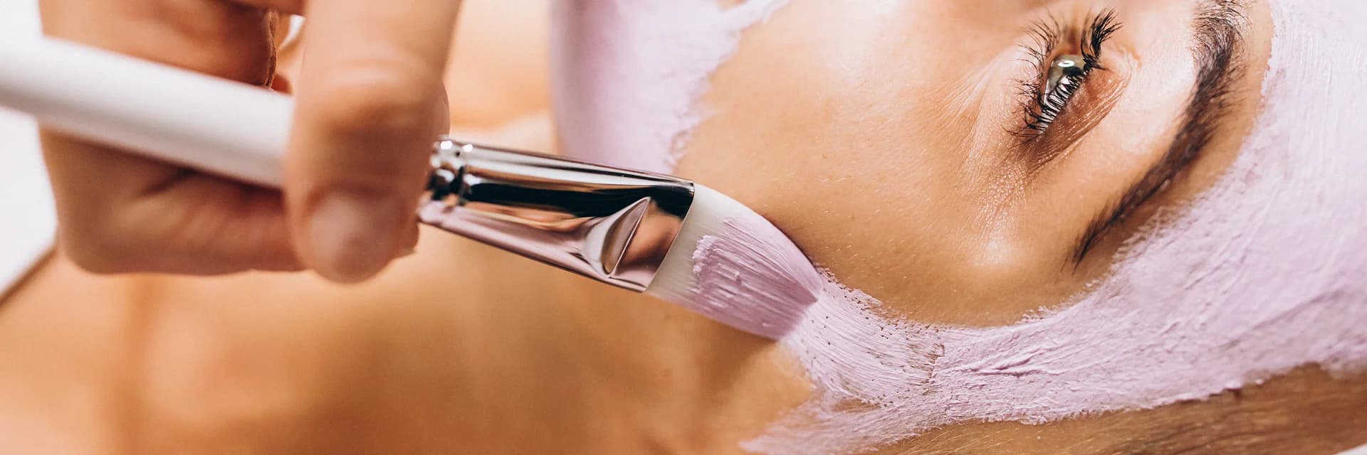 Soft lilac treatment mask being applied to the skin with a brush