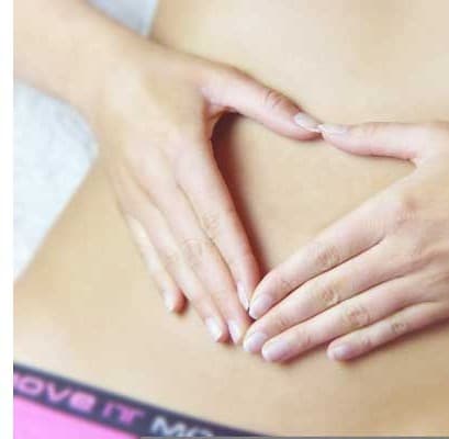 Hands forming a heart shape on a toned stomach
