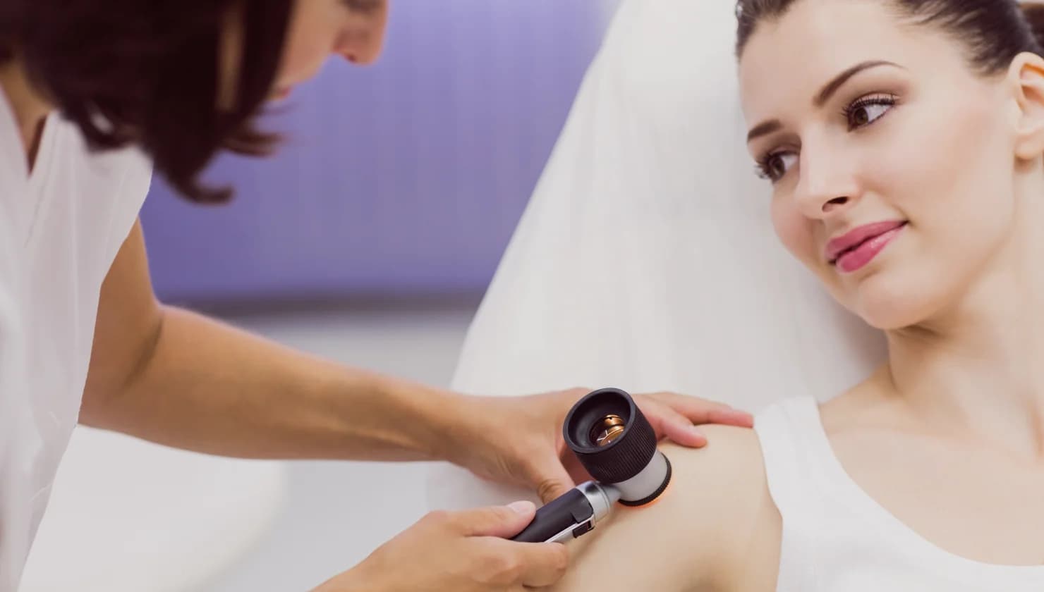 Practitioner examining a skin lesion with a dermatoscope